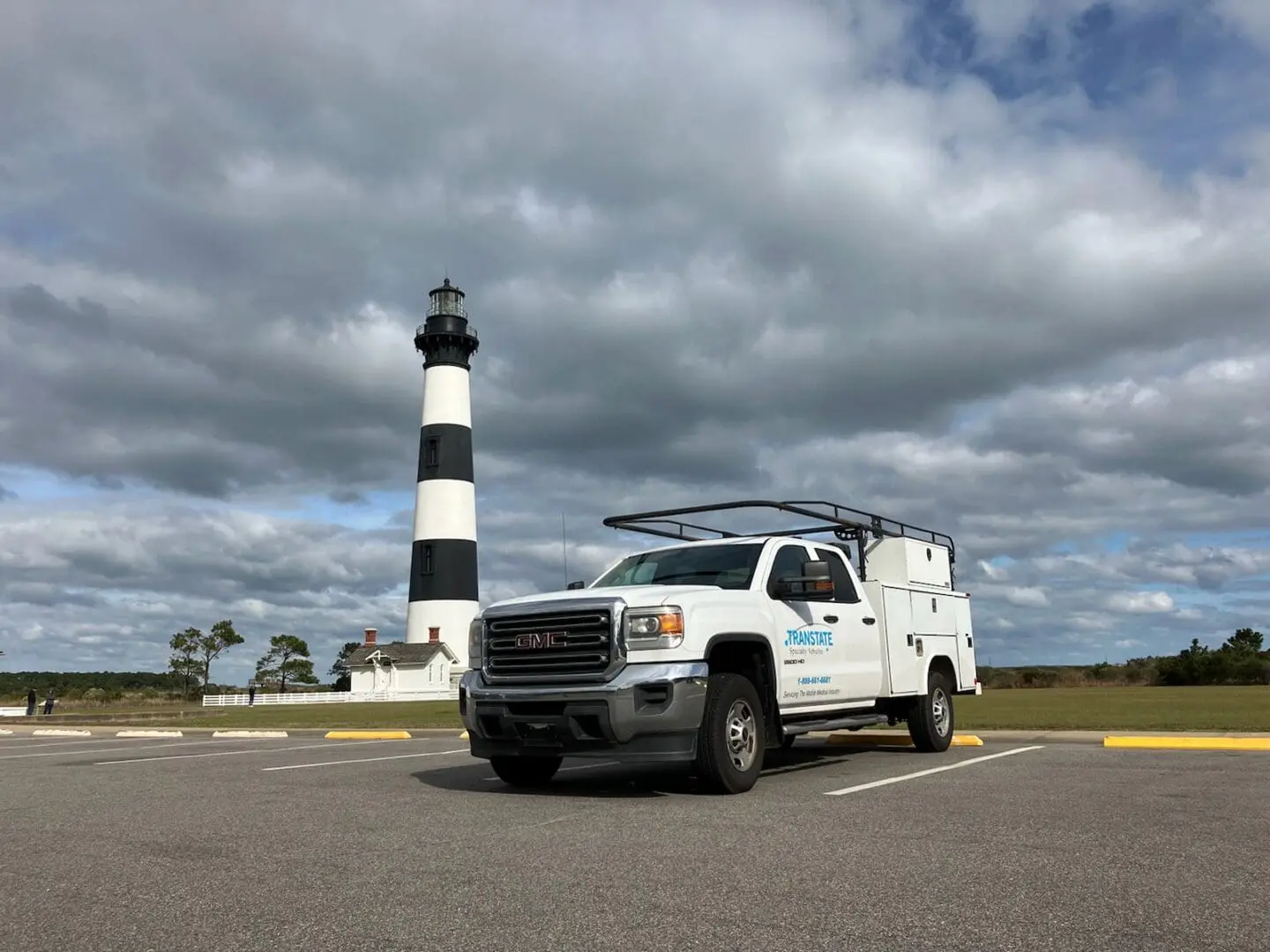 A truck parked in front of a lighthouse.