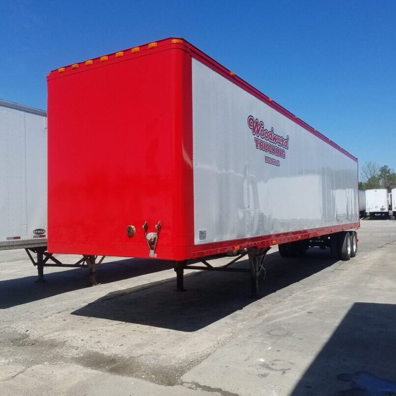 A red and white trailer parked in a lot.